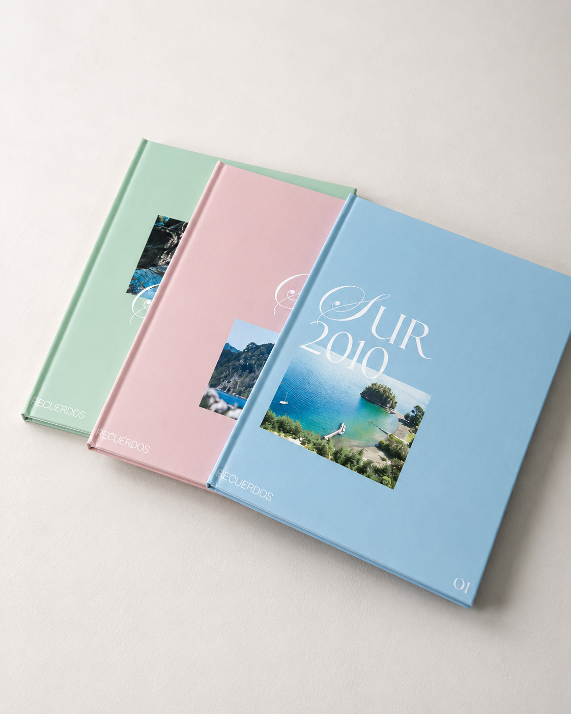 Tres fotolibros de colores pastel con fotos de viajes